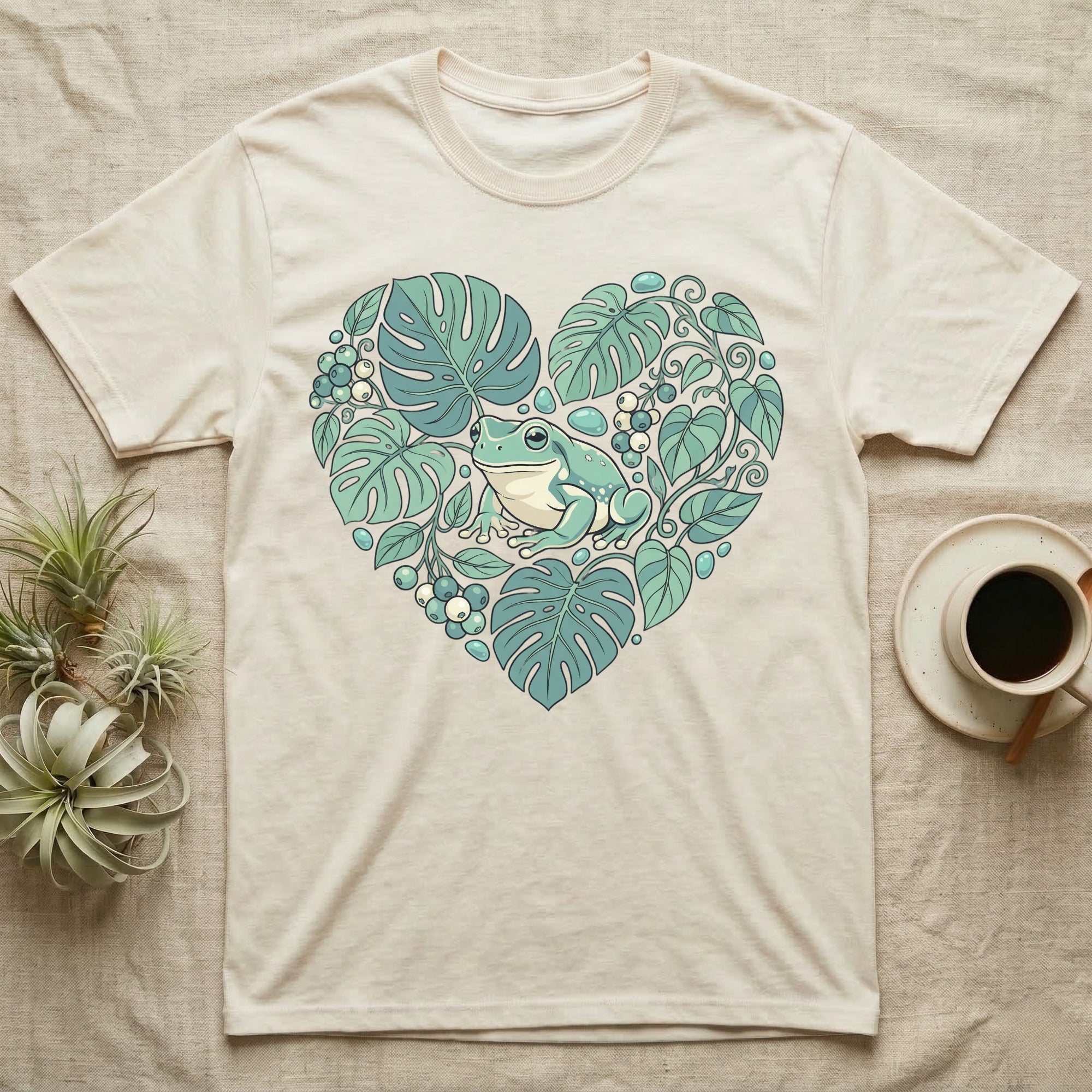 Cream t-shirt with a heart-shaped design of a frog and lush green leaves.