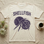 Hermit Crab Shellfish T-Shirt in Natural — Worn purple one-ink print of a hermit crab hugging a big spare shell to its chest under the word Shellfish