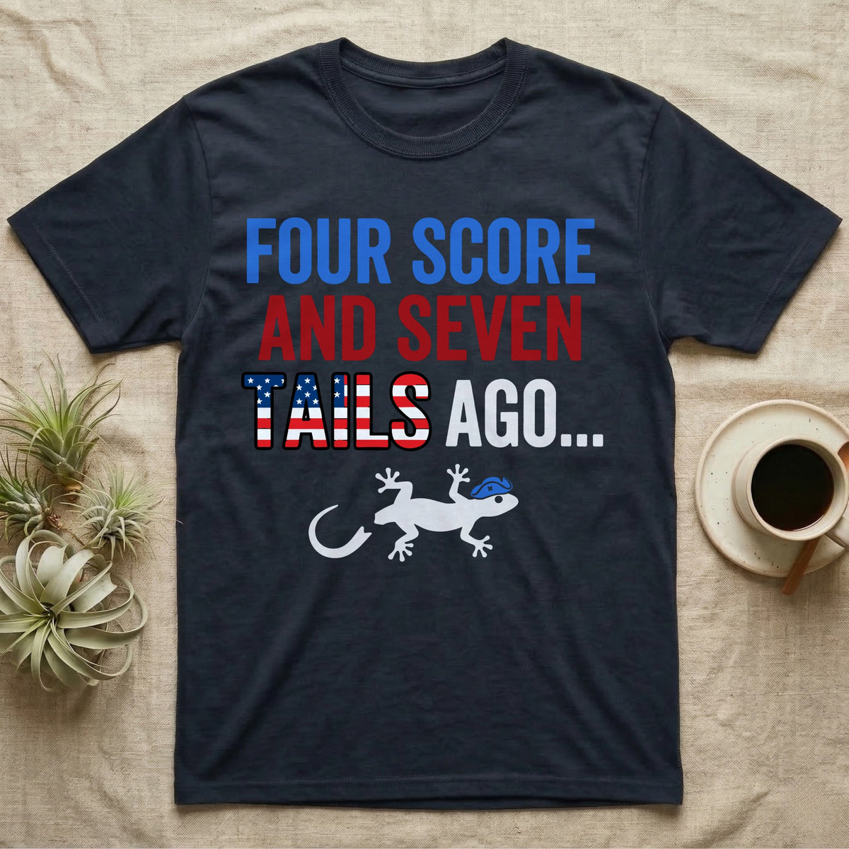Gecko Four Score T-Shirt in Navy — Block text Four Score and Seven Tails Ago with a flag-filled word above a white gecko silhouette shedding its tail.