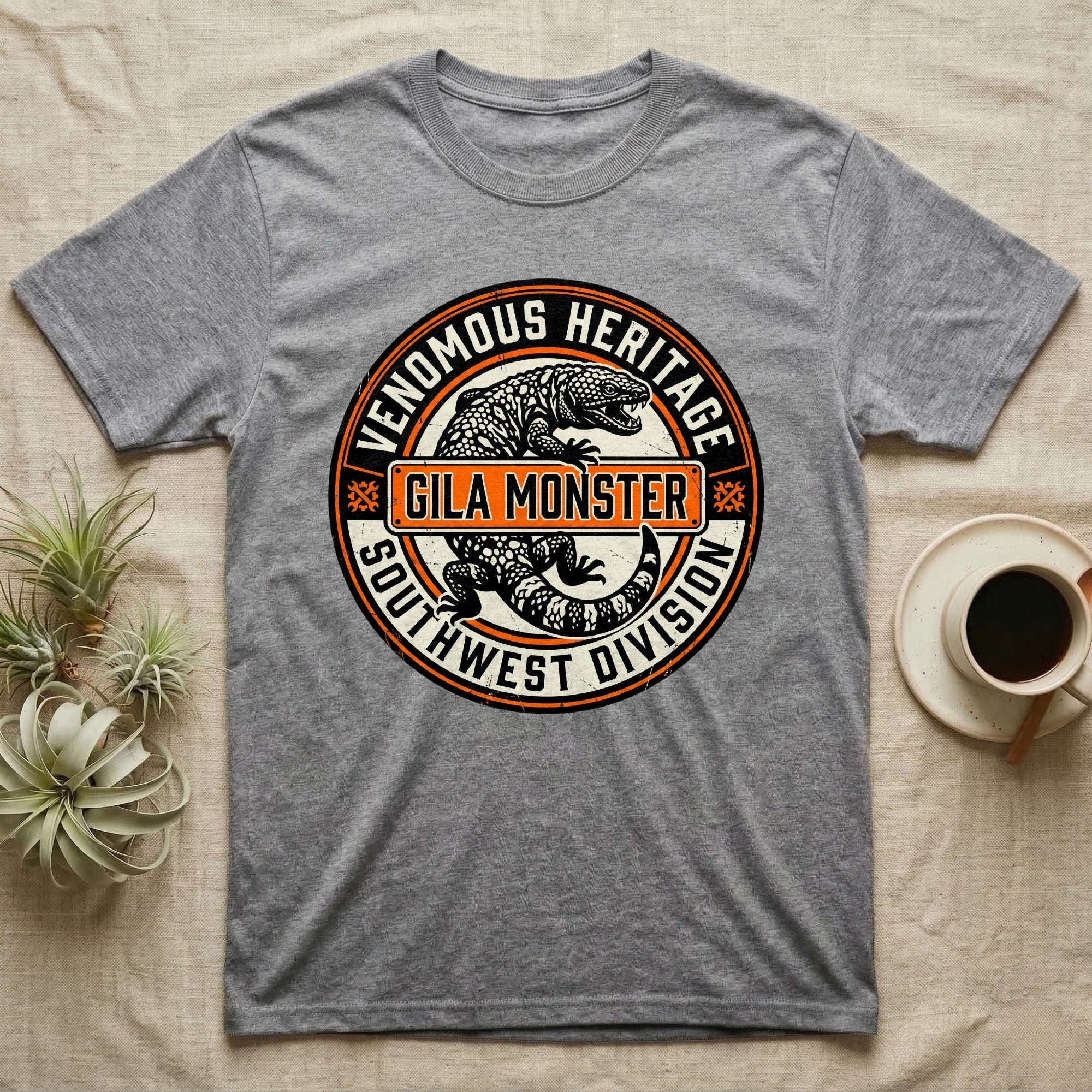 Grey t-shirt featuring a circular graphic with "Venomous Heritage" and "Gila Monster Southwest Division".