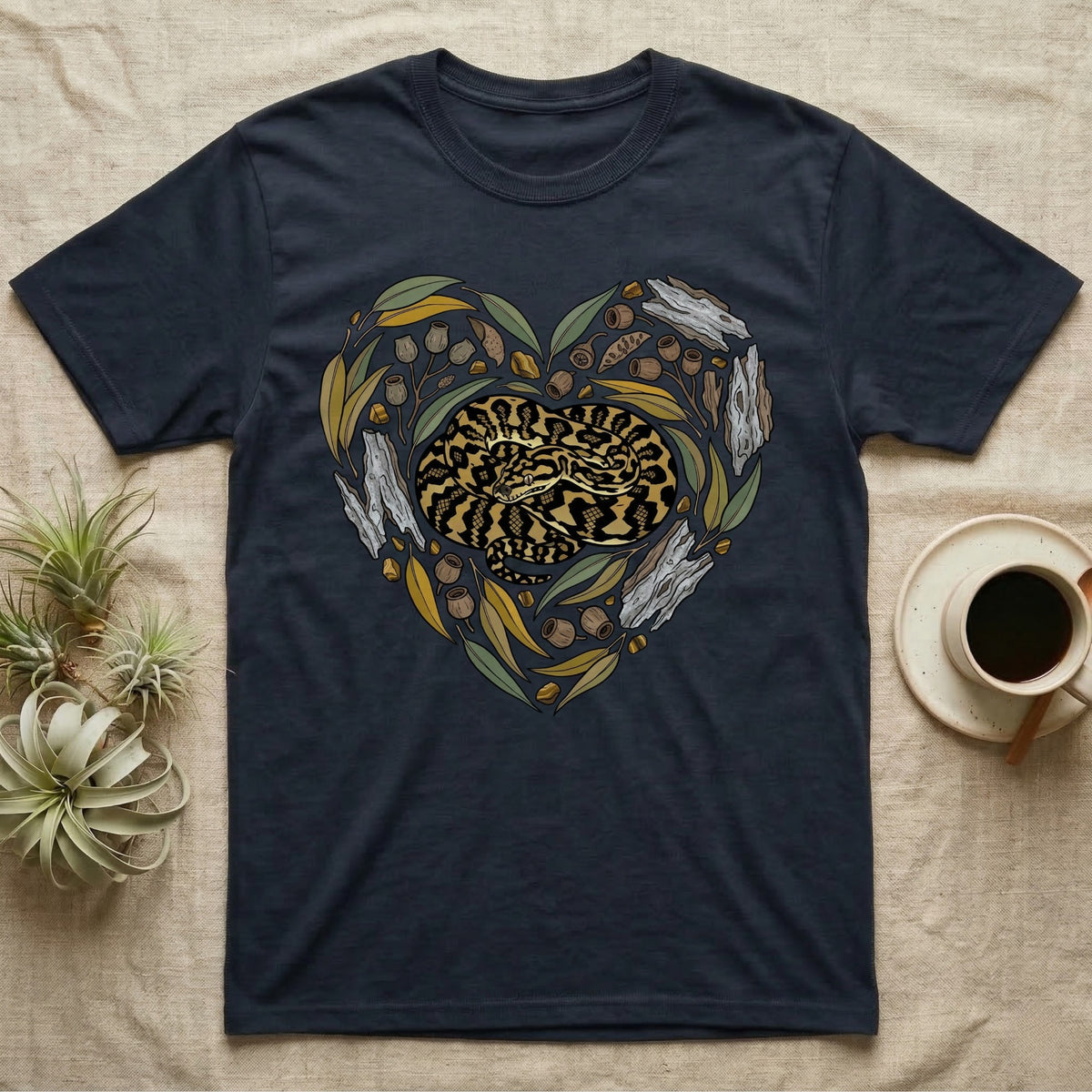 Dark t-shirt with a coiled snake design framed by leaves and branches in a heart shape.