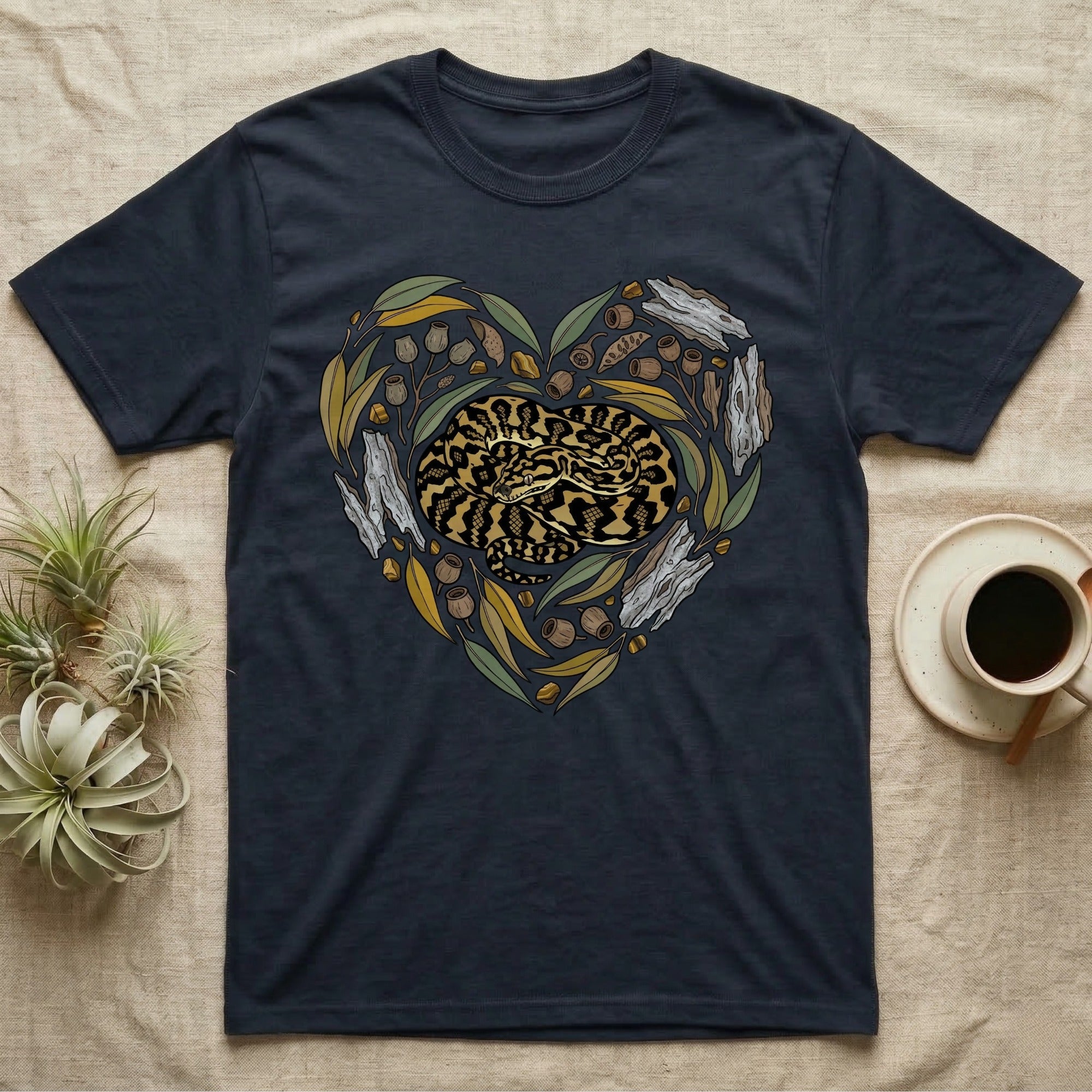 Dark t-shirt with a coiled snake design framed by leaves and branches in a heart shape.