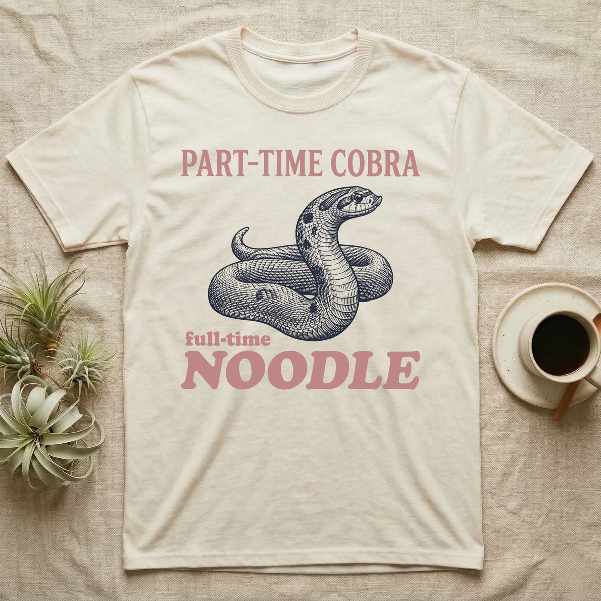 Hognose Snake Noodle T-Shirt in Natural — Navy engraving of a coiled western hognose snake bluffing with a flattened neck between the words PART-TIME COBRA and full-time NOODLE in rose
