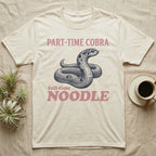 Hognose Snake Noodle T-Shirt in Natural — Navy engraving of a coiled western hognose snake bluffing with a flattened neck between the words PART-TIME COBRA and full-time NOODLE in rose
