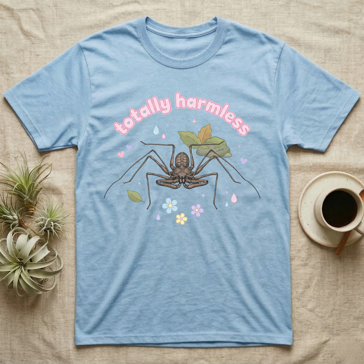 Tailless Whip Scorpion Baby T-Shirt in Light Blue — Pastel tailless whip scorpion with long whip legs among leaves and blossoms, puffy pink wordmark "totally harmless" above.