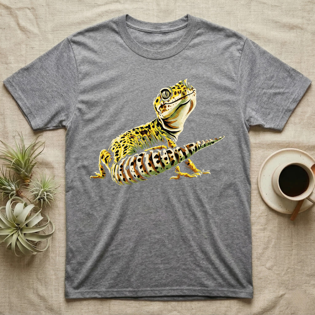 Illustration of a smiling leopard gecko with a plump curled spotted tail, bold vintage-comic ink outlines and halftone shading, graphic-only, no text. — shown on a Sport Grey tee.
