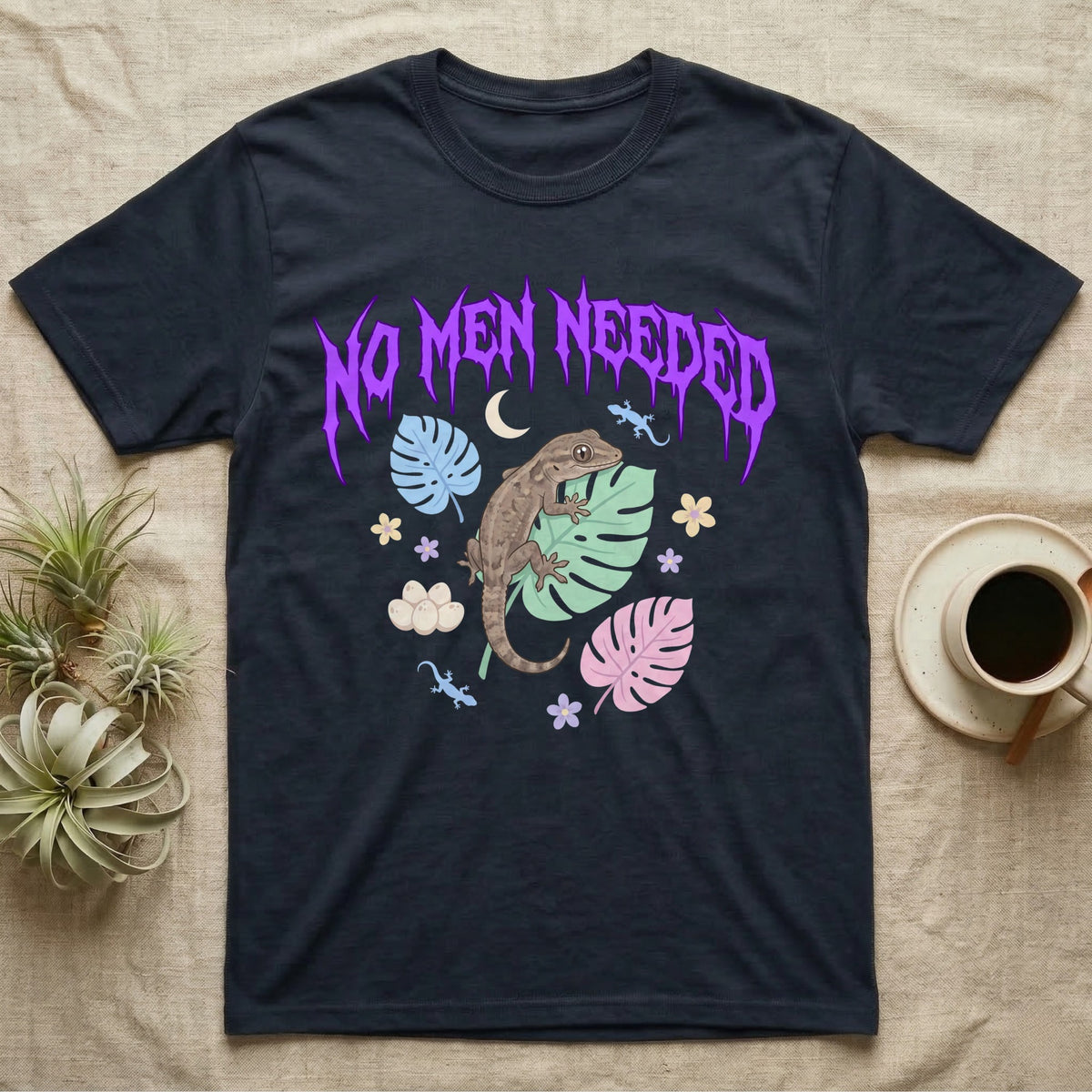 Mourning Gecko Feral T-Shirt in Navy — Mourning gecko on a leaf flanked by clone silhouettes under a jagged violet metal "NO MEN NEEDED" wordmark.