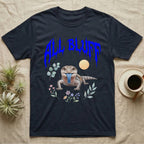Northern Blue-Tongue Skink Feral T-Shirt in Navy — Blue-tongue skink with its blue tongue out under a jagged cobalt-blue metal "ALL BLUFF" wordmark and pastel leaves.