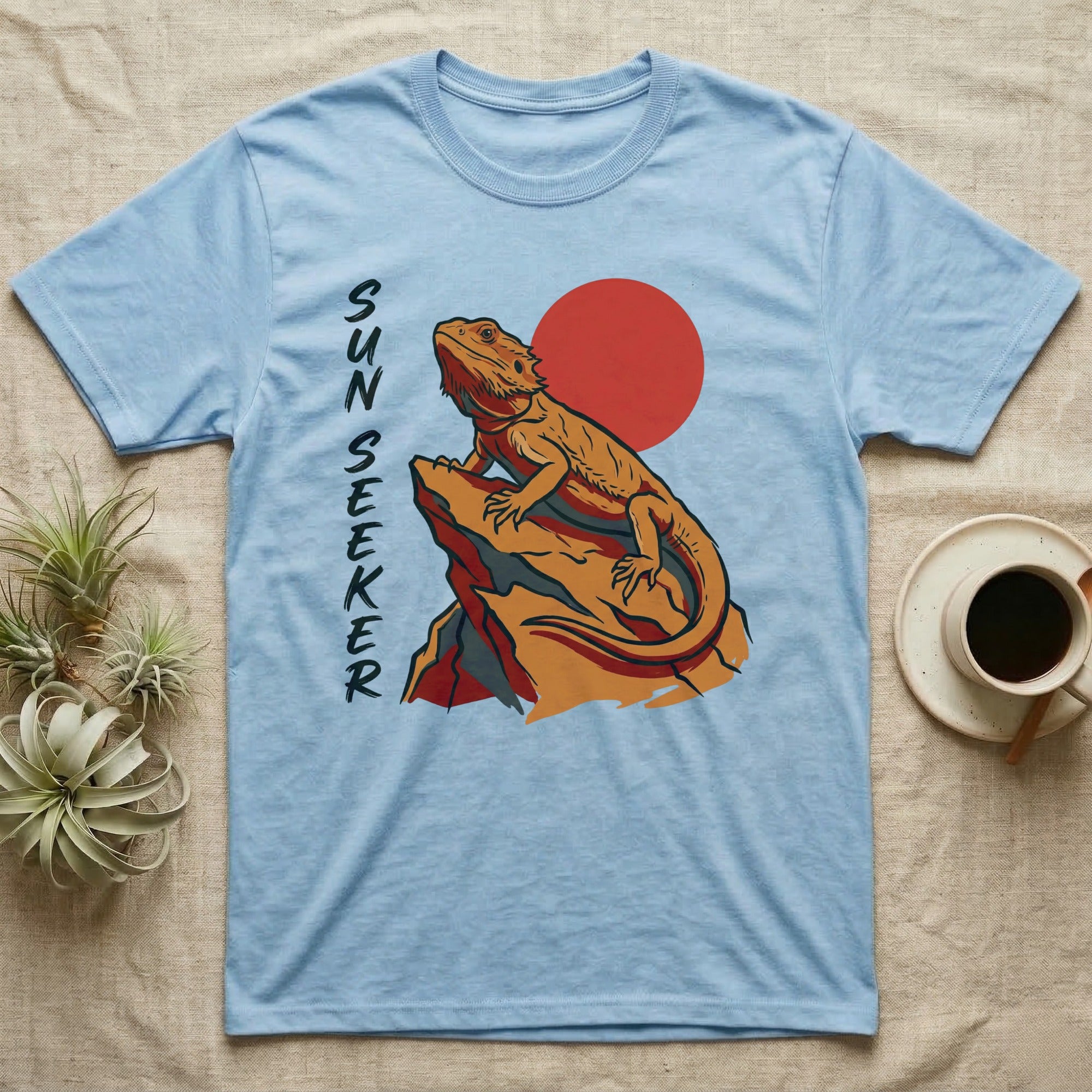 Light blue t-shirt with a bearded dragon on a rock and a red sun graphic.