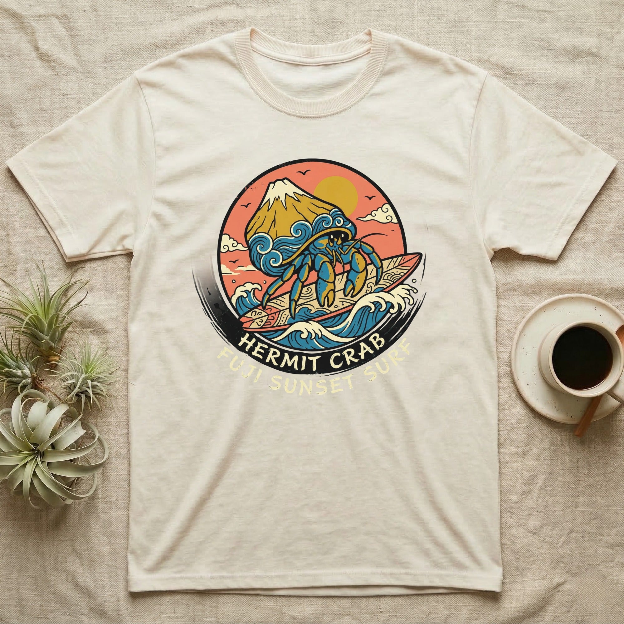 Cream t-shirt with a hermit crab surfing at sunset graphic.