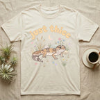 African Fat-Tailed Gecko Softie T-Shirt in Natural — African fat-tailed gecko with a plump tail under a puffy pastel "just thicc" bubble wordmark with tiny hearts.