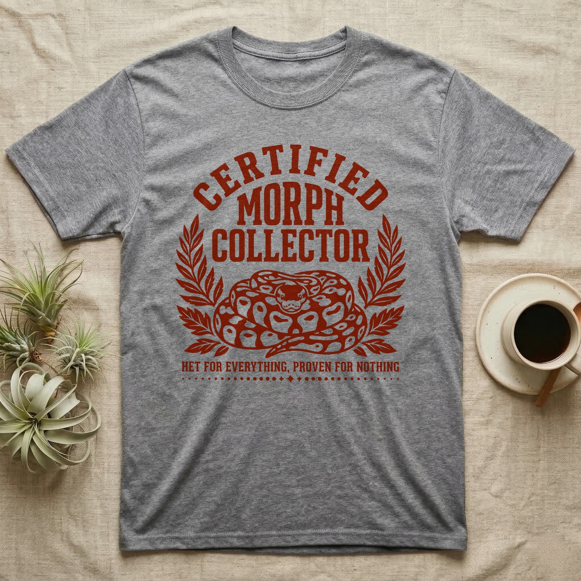 Ball Python Morph Crest T-Shirt in Sport Grey — Linocut-style crest illustration of a coiled ball python with an arched "Certified Morph Collector" headline in rust ink.