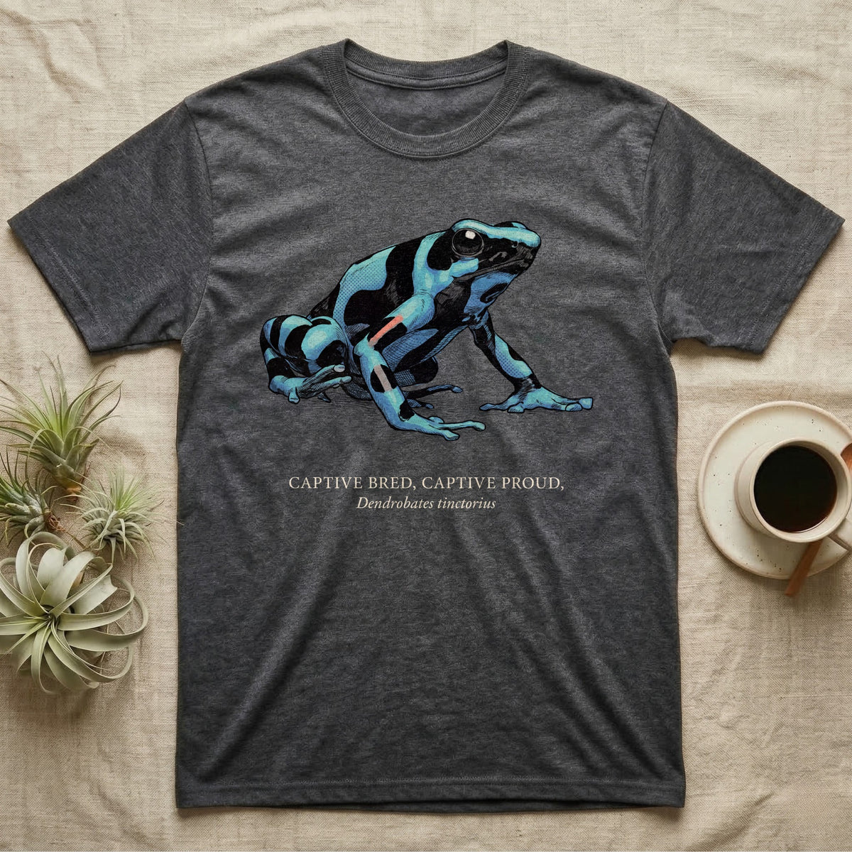 Captive Bred Frog T-Shirt in Dark Heather — Naturalist-plate illustration of a healthy dyeing dart frog above a serif creed reading Captive Bred Captive Proud.