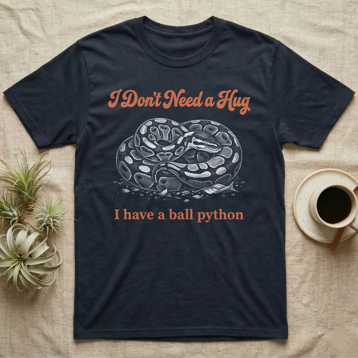 Ball Python Hug T-Shirt in Navy — White-line engraving of a coiled ball python under orange script reading I Don't Need a Hug, I have a ball python