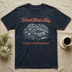 Ball Python Hug T-Shirt in Navy — White-line engraving of a coiled ball python under orange script reading I Don't Need a Hug, I have a ball python
