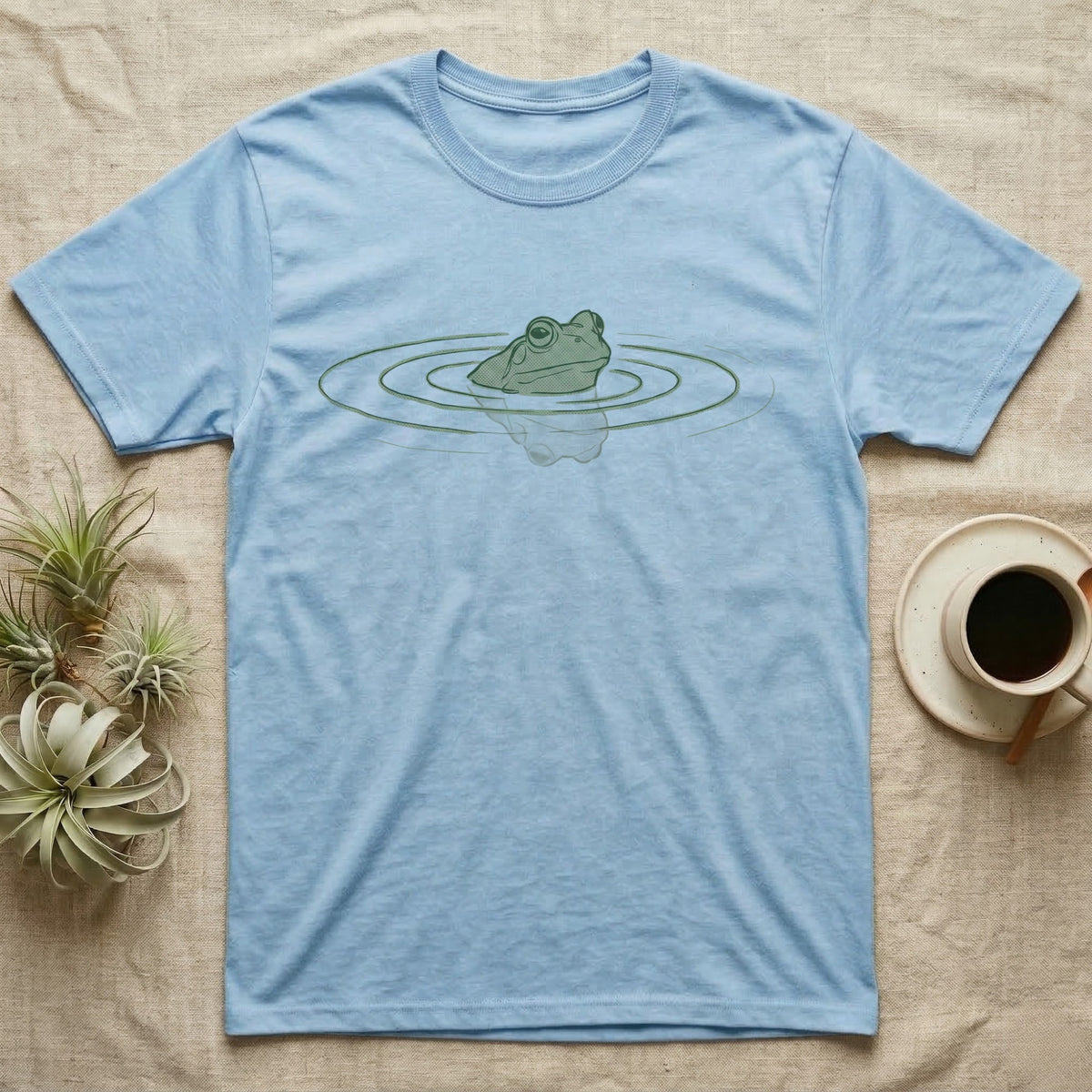 Minimal Swimming Frog T-Shirt in Light Blue — Minimal single-line illustration of a frog at the waterline with concentric ripple rings and vast negative space.