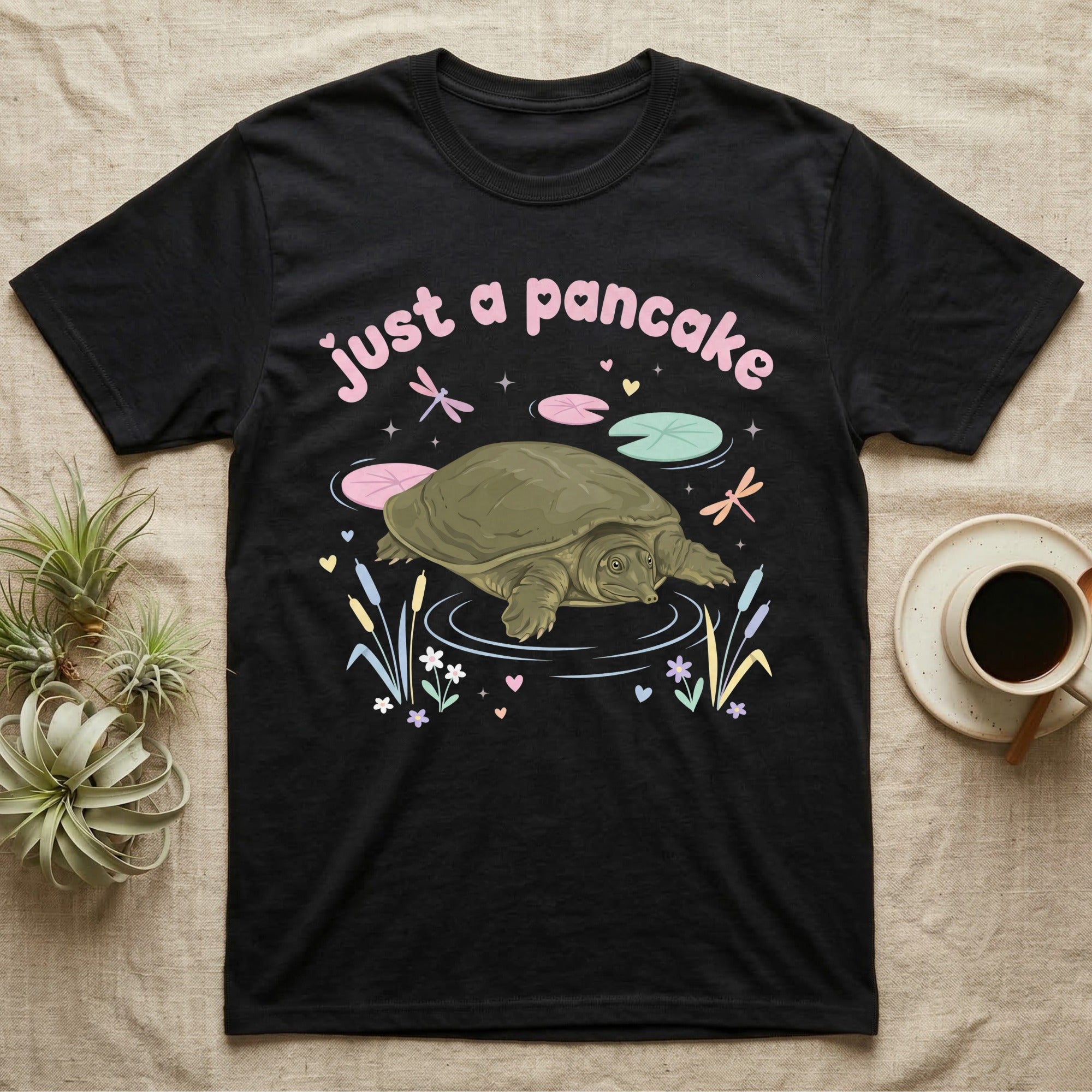 Spiny Softshell Turtle Baby T-Shirt in Black — Pastel spiny softshell turtle with flat shell and snorkel nose among lily pads, puffy pink wordmark "just a pancake" above.