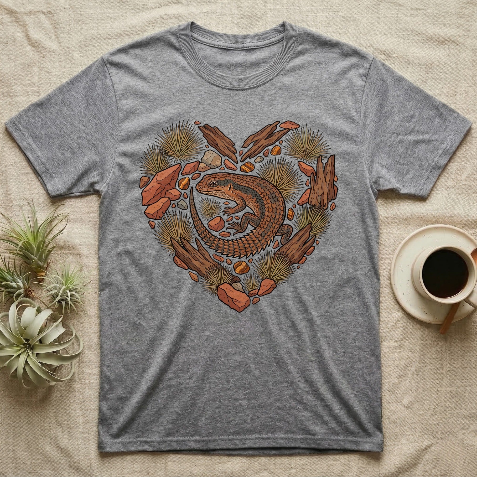 Grey t-shirt with a heart-shaped design of a lizard and natural elements.
