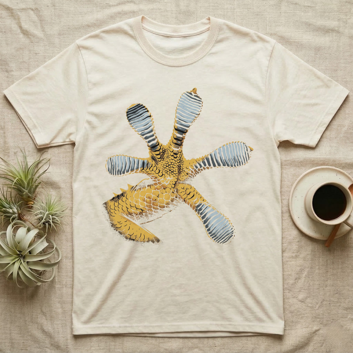 Macro illustration of a gecko's forefoot from underneath, ribbed blue-grey lamellae toe pads fanned against amber-gold scale texture, no on-shirt text. — shown on a Natural tee.
