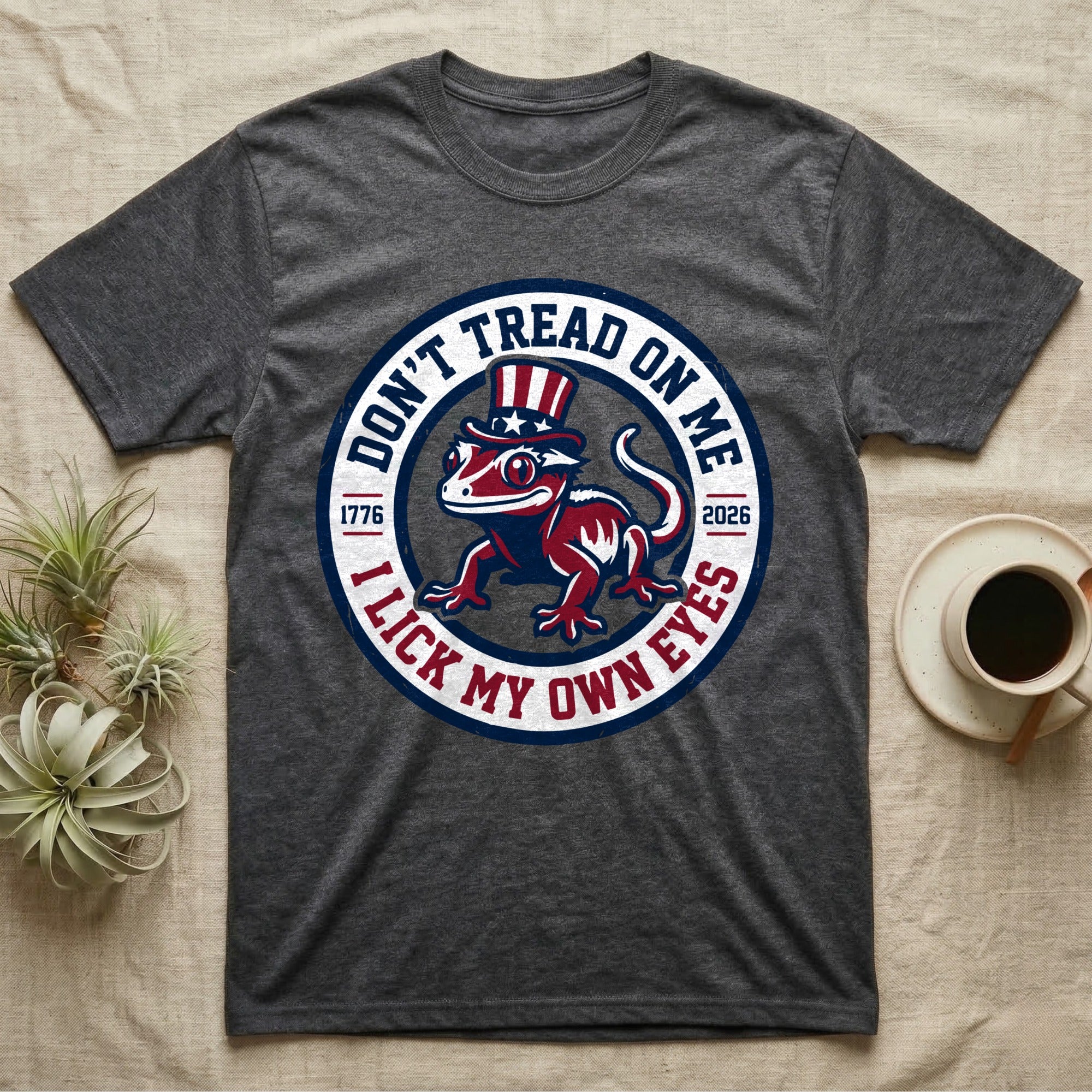 Crested Gecko 1776 T-Shirt in Dark Heather — Distressed crest of a crested gecko in a top hat with text Don't Tread On Me and I Lick My Own Eyes.