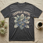 Tadpole Hotel Frog T-Shirt in Dark Heather — Whimsical naturalist illustration of a dart frog tucking tadpoles into a bromeliad Tadpole Hotel with hand-lettered marquee text.