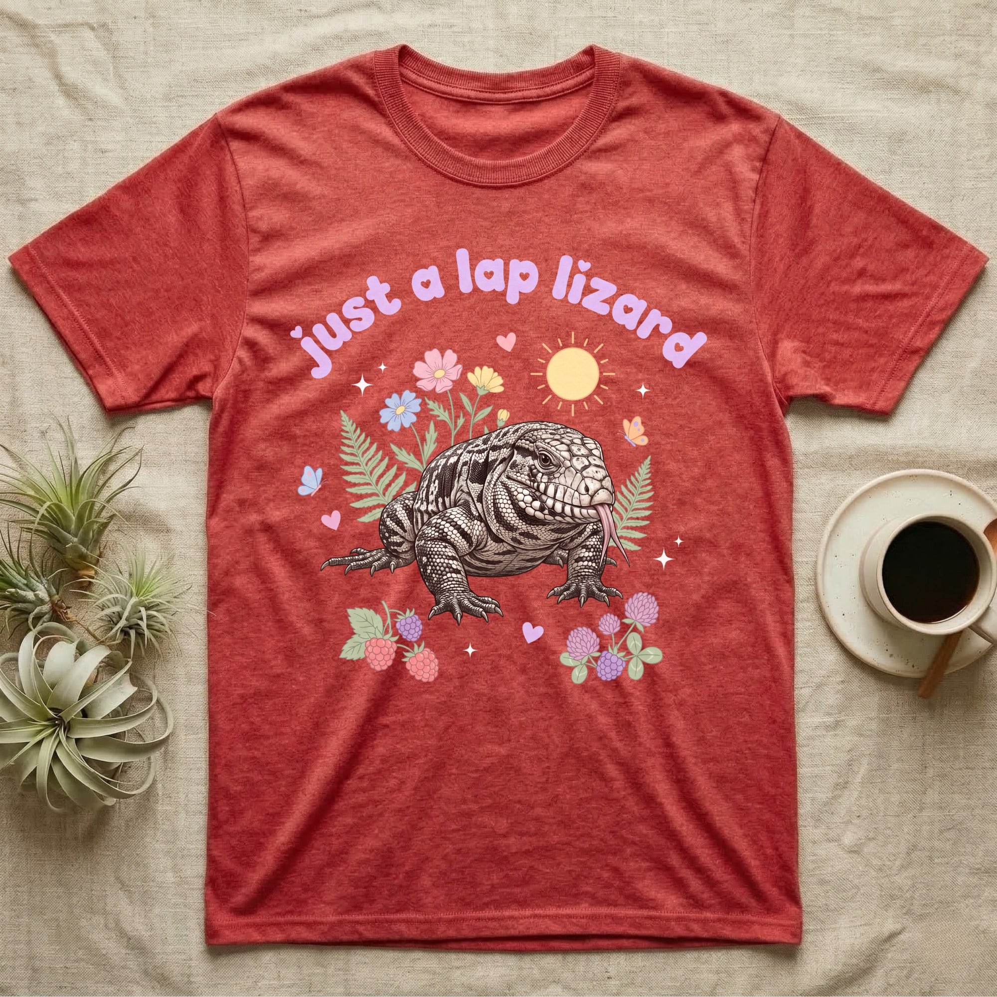 Argentine Tegu Baby T-Shirt in Heather Red — Black-and-white Argentine tegu with forked tongue among pastel flowers under puffy lavender text "just a lap lizard".