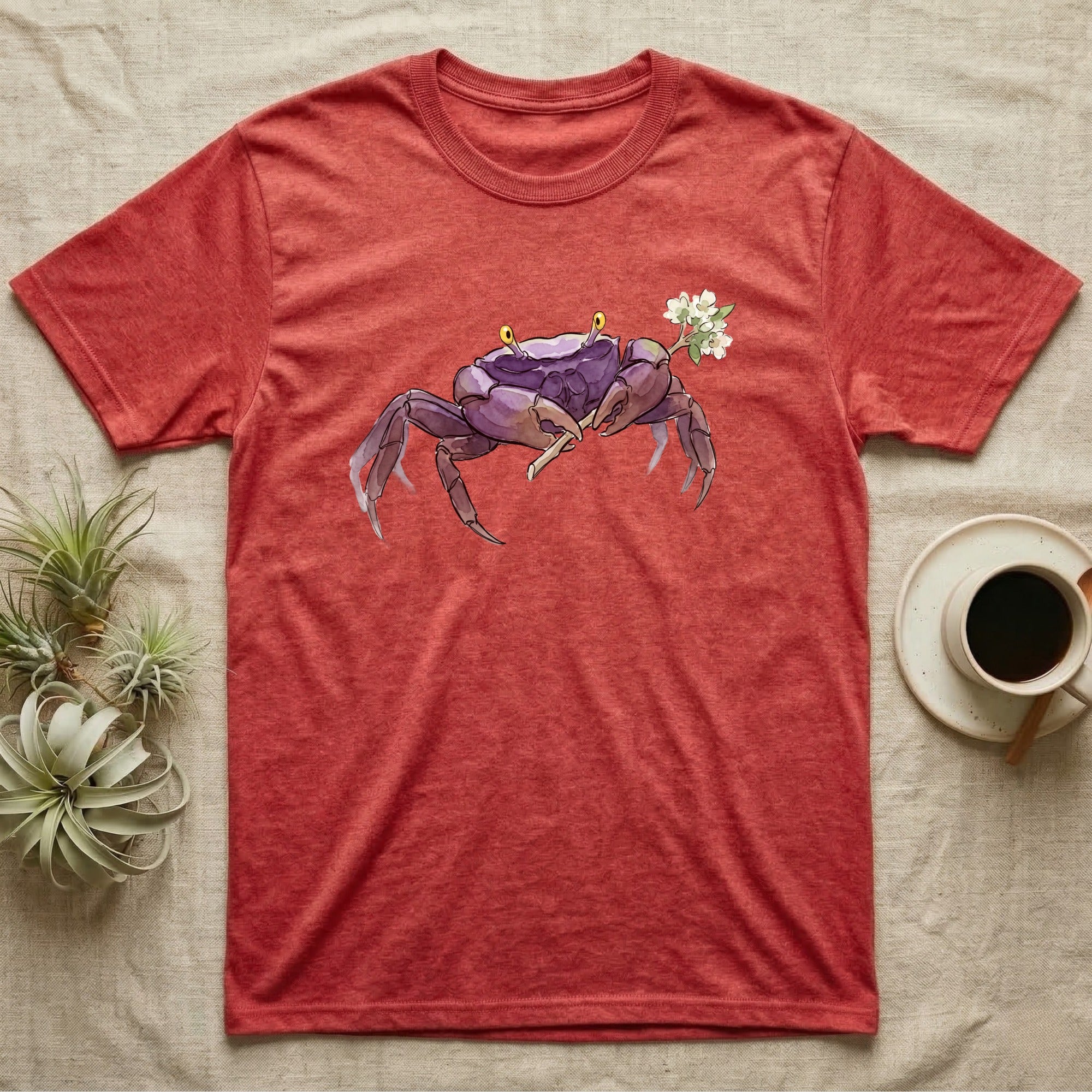Vampire Crab Blossom T-Shirt in Heather Red — Watercolor illustration of a violet-purple vampire crab with yellow eye stalks holding a moss-flower blossom sprig, on a dark grey t-shirt.