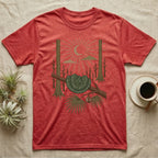 Green Tree Python Home Range T-Shirt in Heather Red — Woodcut-style illustration of a green tree python coiled in a saddle over a branch with palms and tall trunks behind, no on-shirt text.