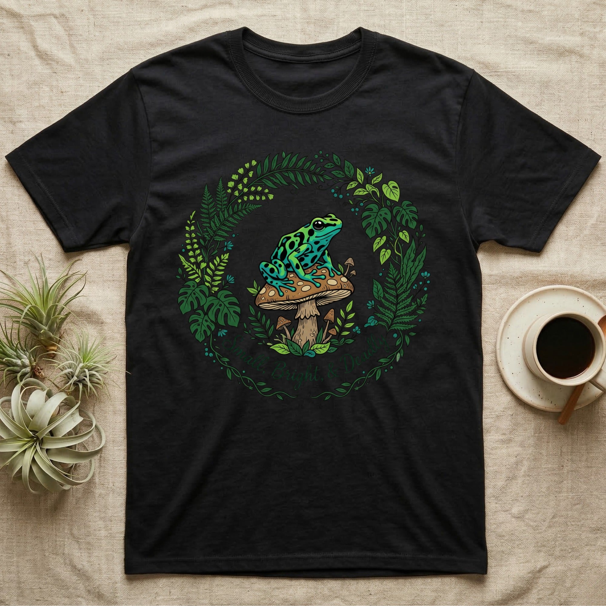 Black t-shirt with a circular floral design featuring a frog on a mushroom.