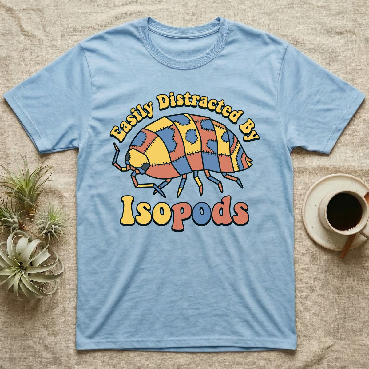 Dairy Cow Isopod Patchwork T-Shirt in Light Blue — Quilt-patchwork dairy cow isopod in mustard and denim under retro "Easily Distracted By Isopods" text.