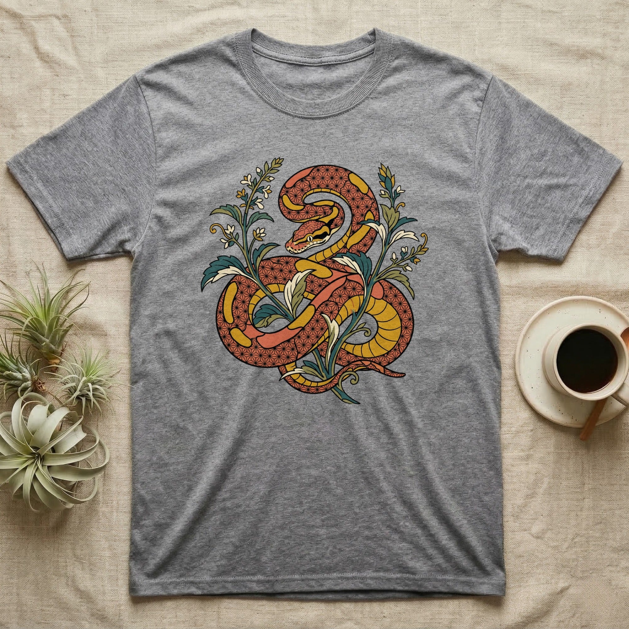 Grey t-shirt with a stylized orange and yellow snake design surrounded by green leaves.