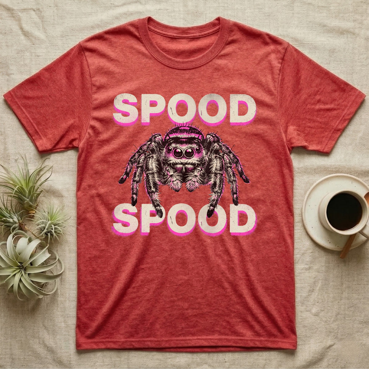 Spood Jumping Spider T-Shirt in Heather Red — Grunge-punk illustration of an oversized front-facing jumping spider with a distressed "Spood" wordmark in bone and acid pink.