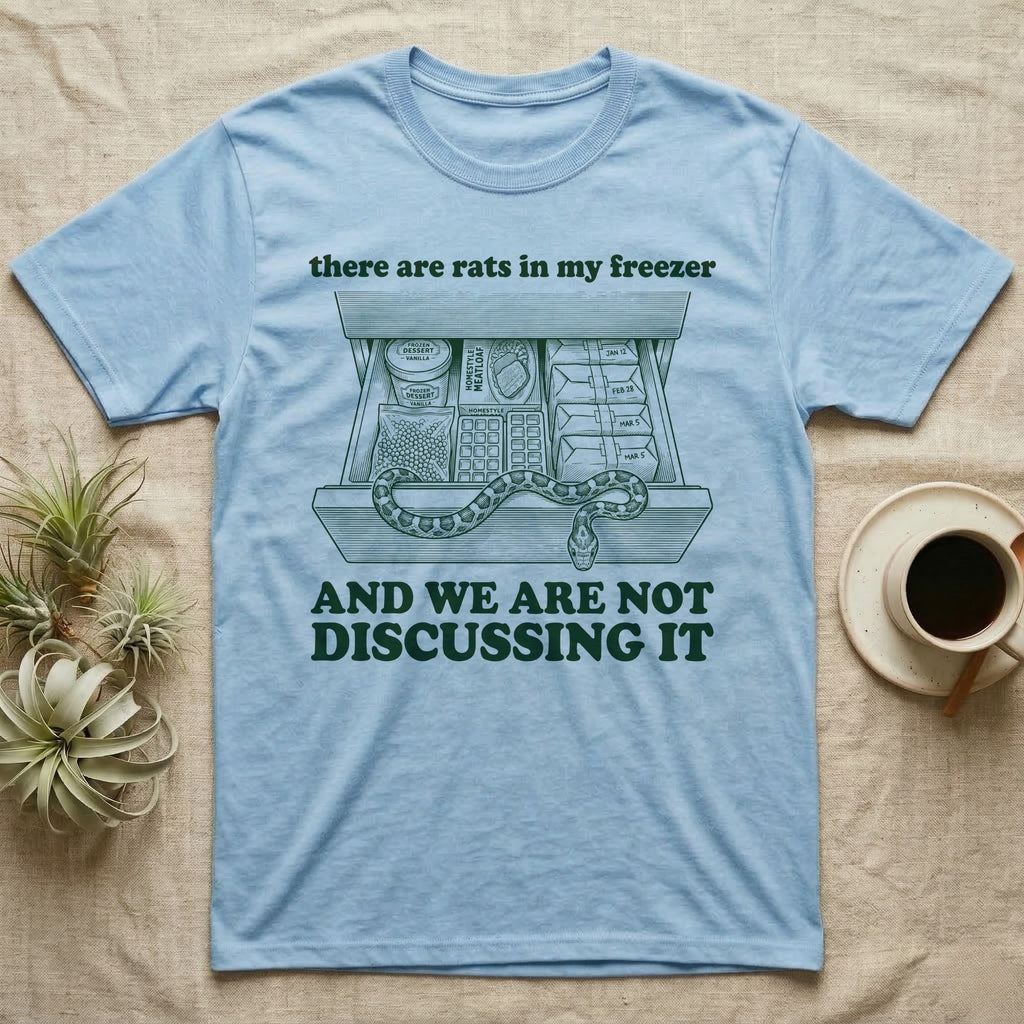 Corn Snake Freezer T-Shirt in Light Blue — Engraved corn snake draped over an open kitchen freezer drawer of food and dated parcels, between there are rats in my freezer and AND WE ARE NOT DISCUSSING IT.