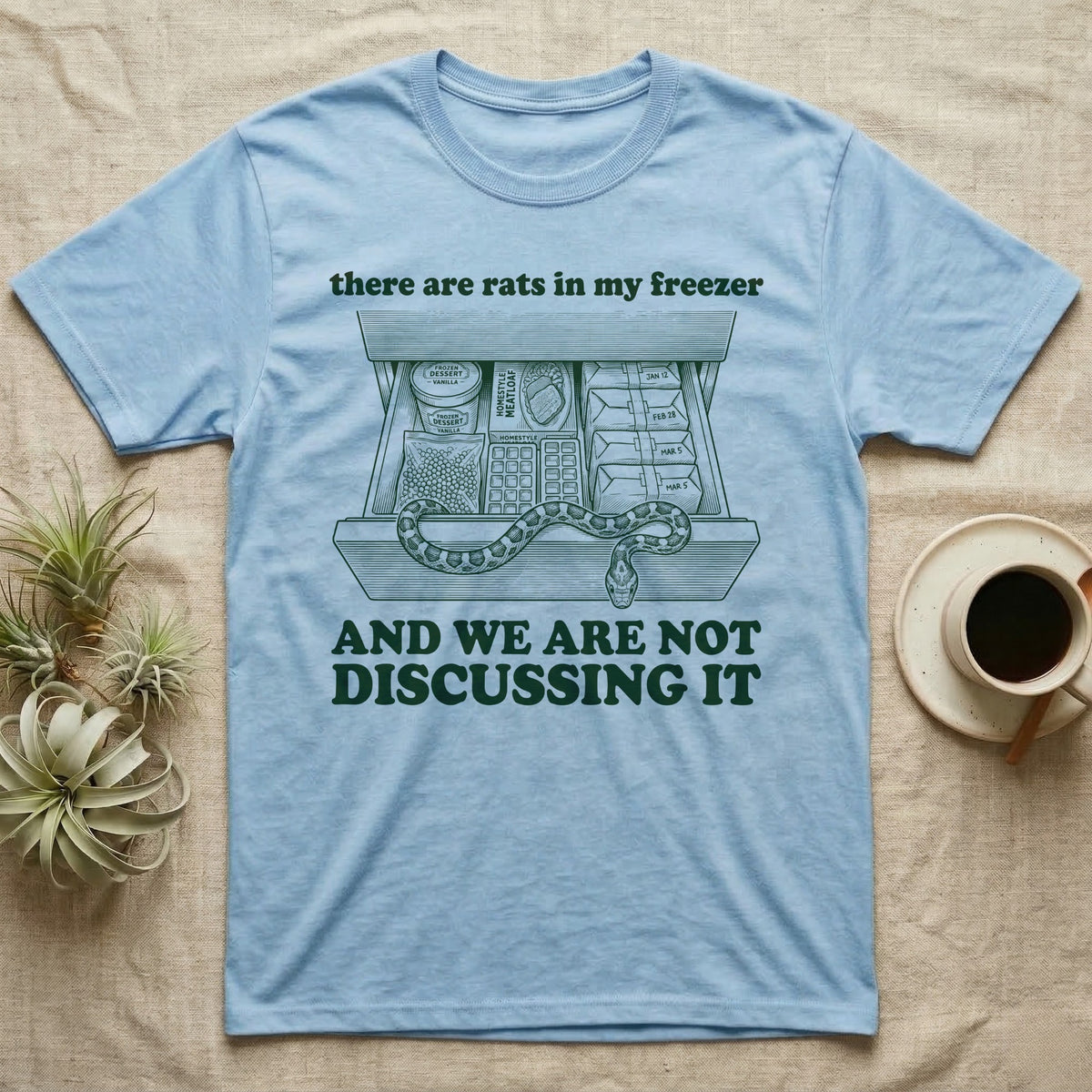 Corn Snake Freezer T-Shirt in Light Blue — Engraved corn snake draped over an open kitchen freezer drawer of food and dated parcels, between there are rats in my freezer and AND WE ARE NOT DISCUSSING IT.