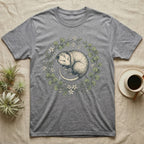 Grey t-shirt with illustration of a sleeping opossum within a floral wreath.