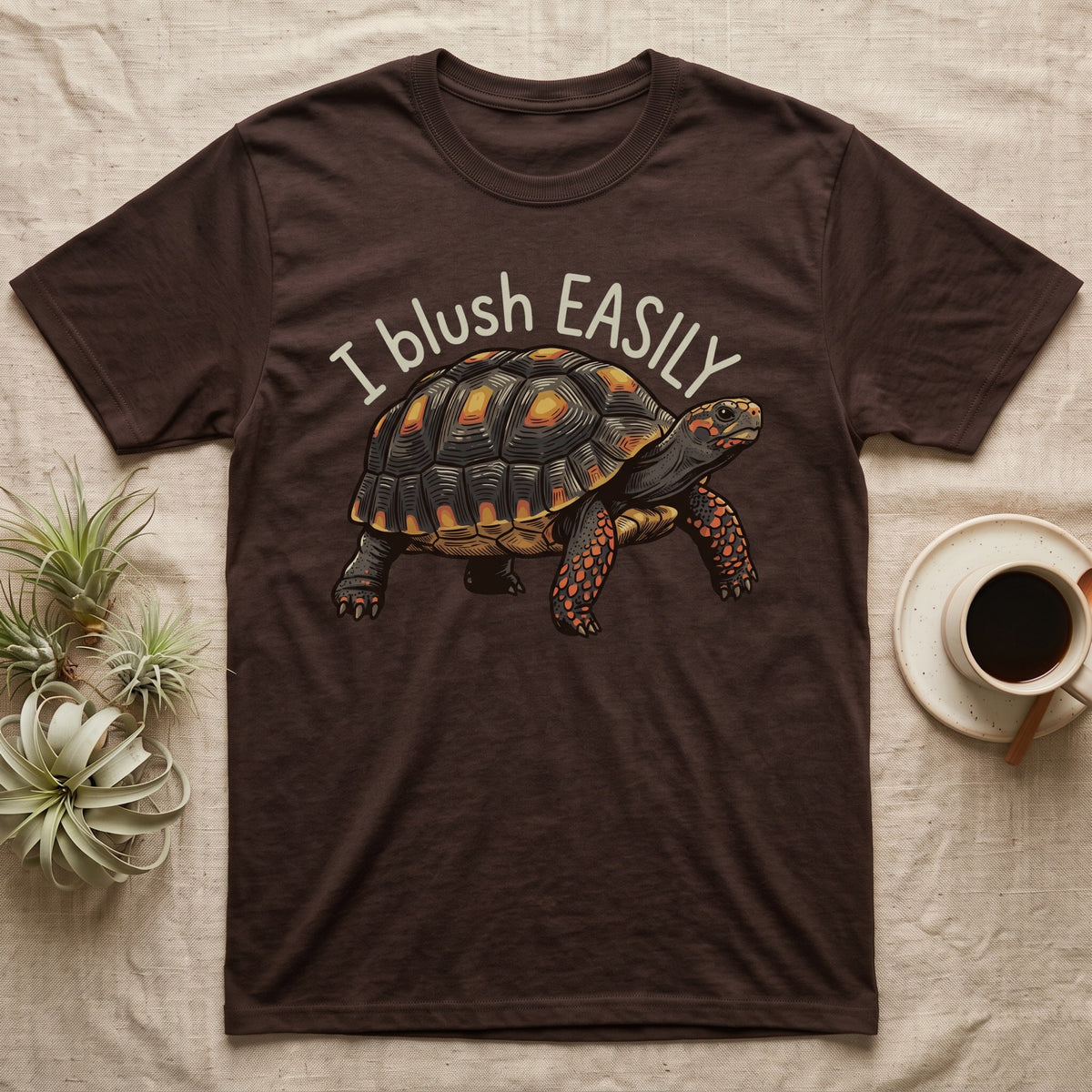 Red-Foot Tortoise Blush T-Shirt in Dark Chocolate — Red-footed tortoise with red-orange cheeks and legs walking under the curved words I blush EASILY