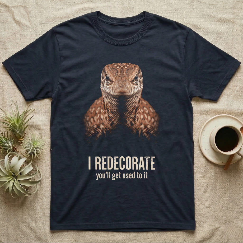 Deadpan mugshot of a rust-brown ackie monitor on black, captioned I redecorate, you'll get used to it. — shown on a Navy tee.