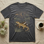 Leopard Gecko Home Range T-Shirt in Dark Heather — Woodcut-style illustration of a leopard gecko standing on cracked earth beside flat stones with thorn scrub behind, no on-shirt text.