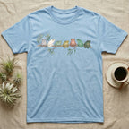 White's Tree Frog Canopy Crew T-Shirt in Light Blue — Watercolor illustration of seven White's tree frogs in different colour phases on a eucalyptus branch, dark grey T-shirt design.