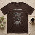 Ackie Monitor Burrow T-Shirt in Dark Chocolate — Chalk-white science diagram of an ackie monitor curled at the bottom of a deep winding burrow, under the words IN TOO DEEP and AGAIN