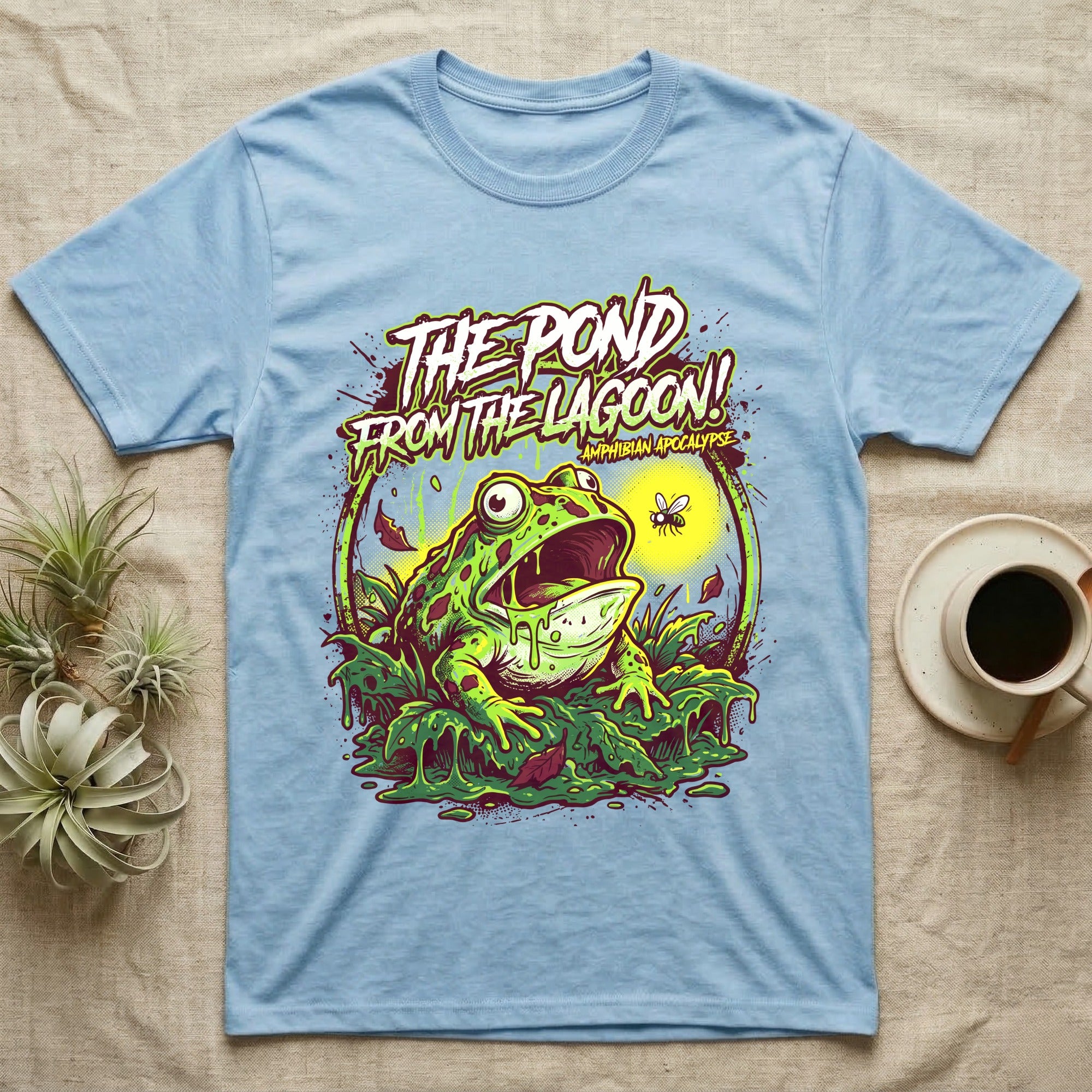 Pacman Frog Lagoon Apocalypse T-Shirt in Light Blue — B-movie horror poster of a Pacman frog bursting from slime at a fly, "The Pond From the Lagoon, Amphibian Apocalypse."