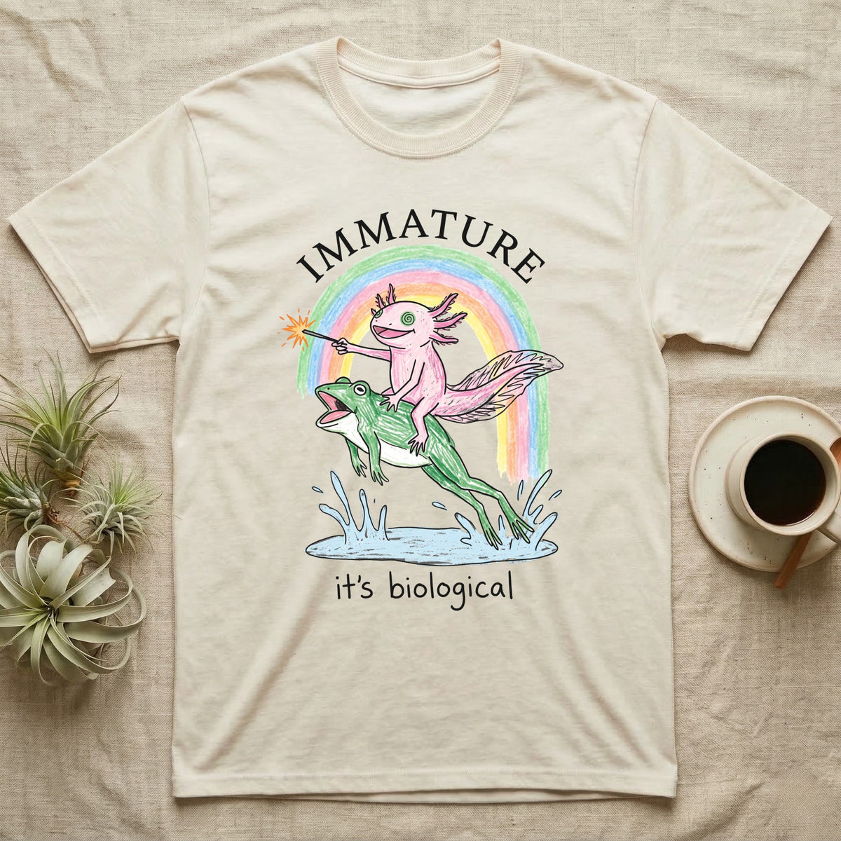 Axolotl Immature T-Shirt in Natural — Crayon drawing of a pink axolotl riding a leaping green frog through a rainbow, sparkler lit, under IMMATURE