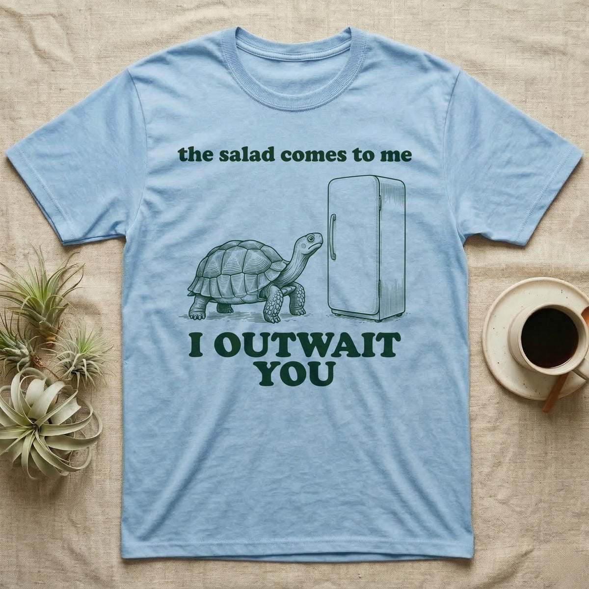 Sulcata Fridge Standoff T-Shirt in Light Blue — Engraved sulcata tortoise waiting in front of a closed fridge between the words the salad comes to me and I OUTWAIT YOU.