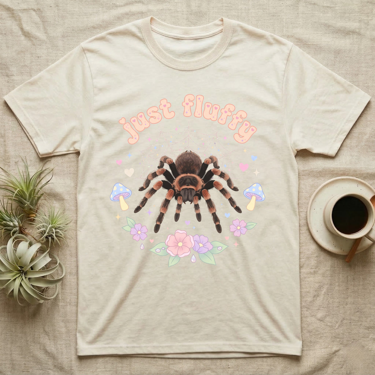 Mexican Redknee Tarantula Baby T-Shirt in Natural — Fuzzy Mexican redknee tarantula on a pastel web with blossoms under puffy peach bubble text "just fluffy".