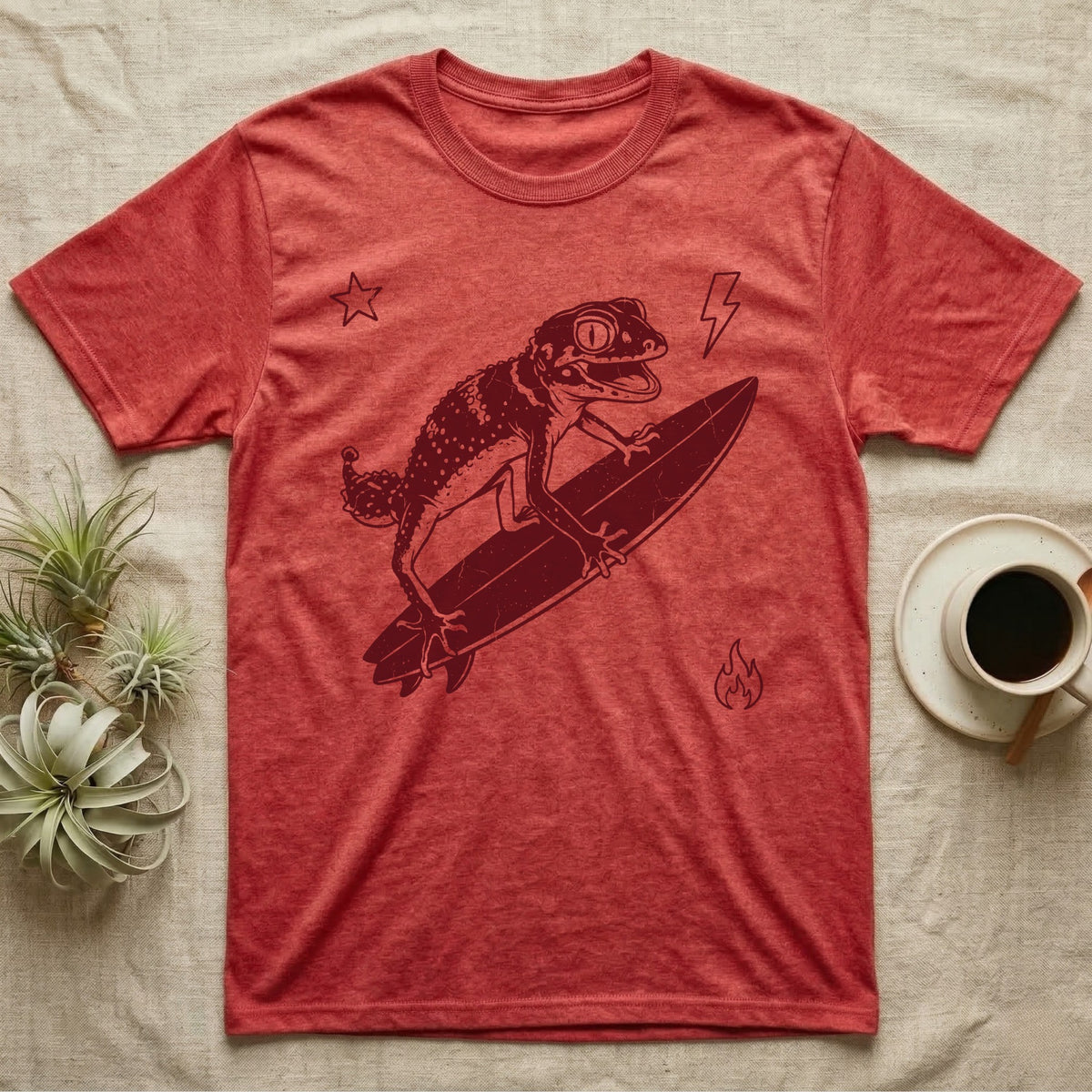 Knob-Tailed Gecko Surfing T-Shirt in Heather Red — Distressed one-ink illustration of a knob-tailed gecko riding a surfboard, airborne at the peak of an aerial.