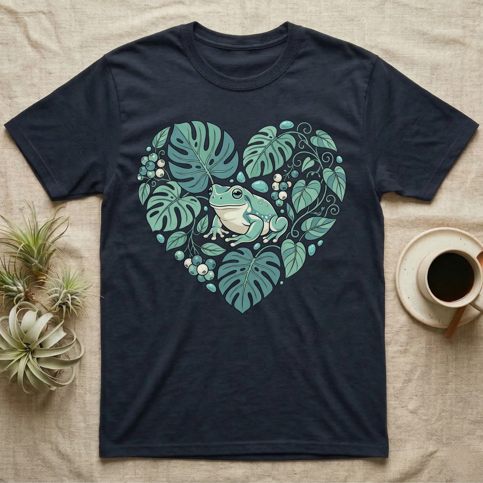 Dark t-shirt with a heart-shaped design of a frog and tropical leaves.