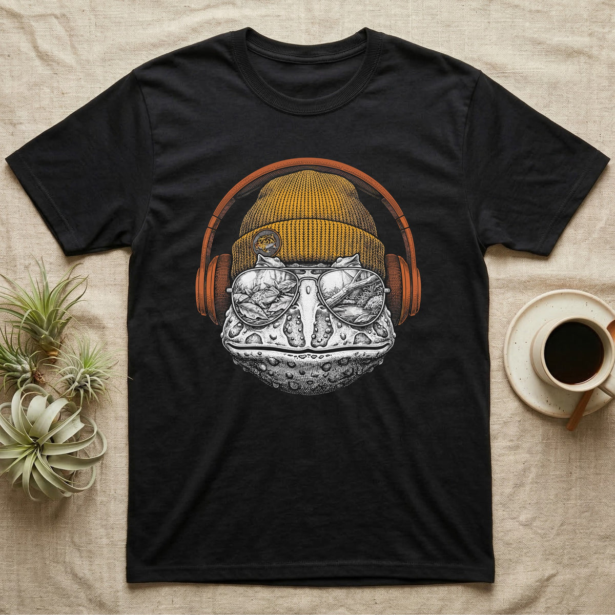 Pacman Frog Chill Beats T-Shirt in Black — Engraved Pacman horned frog with wide bumpy skin in a beanie and headphones, aviators reflecting a woodland pond.