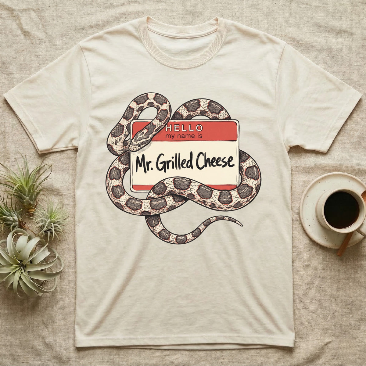 Grilled Cheese Corn Snake T-Shirt in Natural — Flat retro illustration of a corn snake coiled through a "Hello my name is Mr. Grilled Cheese" name-tag badge.