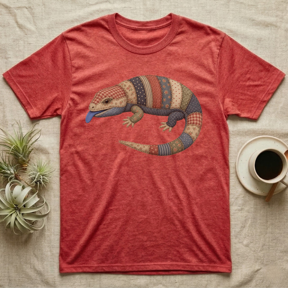 Red heather t-shirt with a patchwork lizard design and blue tongue.
