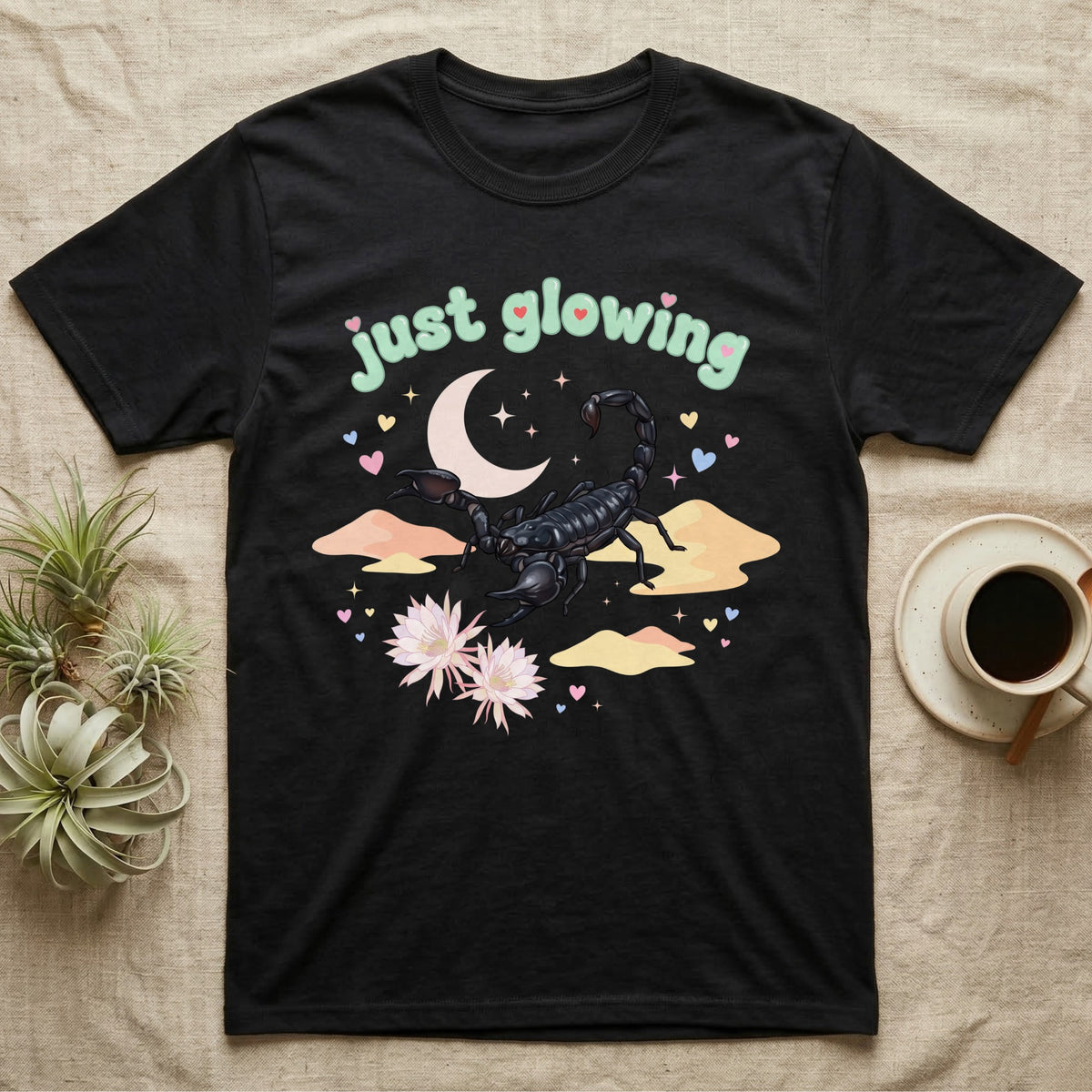 Emperor Scorpion Baby T-Shirt in Black — Black emperor scorpion, pincers raised, under a pastel moon and stars with puffy mint bubble text "just glowing".